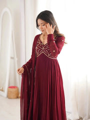 Woman wearing a burgundy dress with intricate detailing in a bright room.