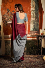 Woman in a traditional outfit with a red and gray saree in an ornate room.