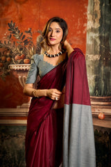 Woman in a maroon and gray saree standing against an ornate wall.