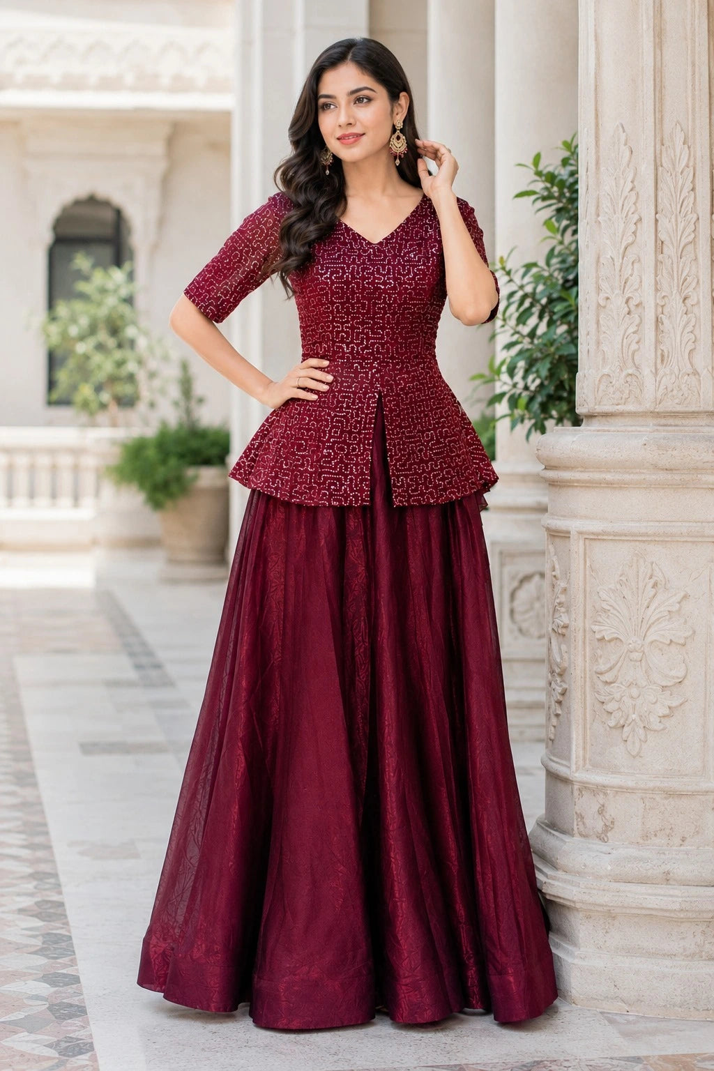 Woman wearing a maroon peplum top and long skirt standing in an elegant outdoor setting.