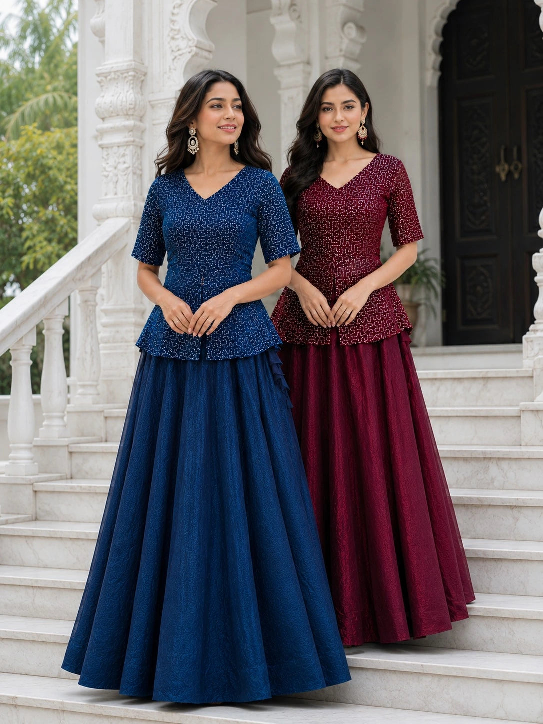 Two women in blue and maroon traditional outfits standing on steps.