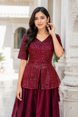 Woman wearing a maroon patterned dress standing against an architectural background