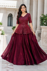 Woman wearing a burgundy evening gown with sequin top in an outdoor setting.