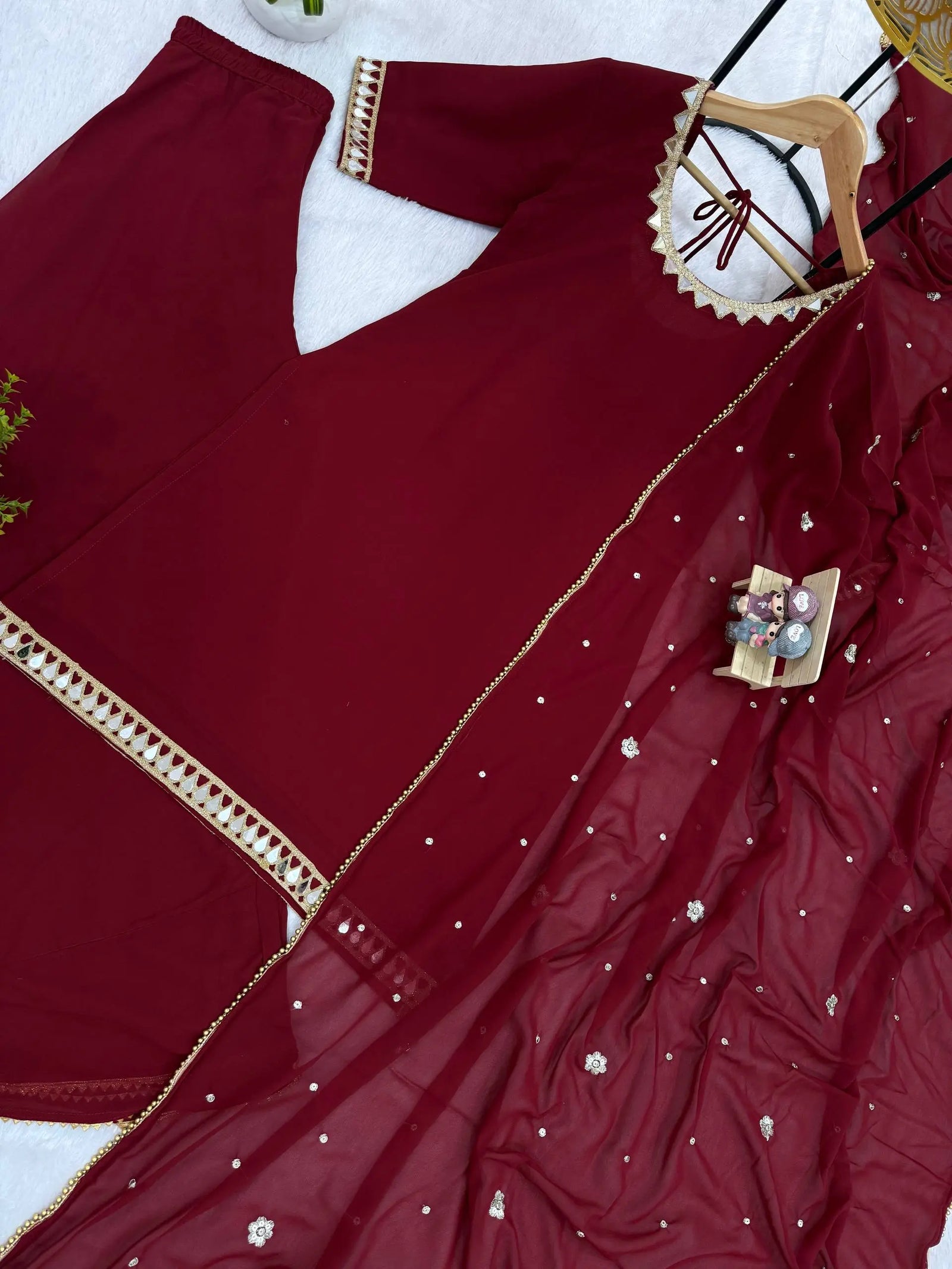 Maroon saree with gold border and floral embellishments on a white background
