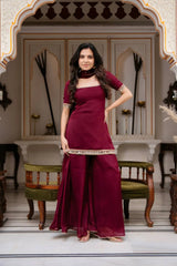Woman in a maroon traditional outfit standing in an ornate room.