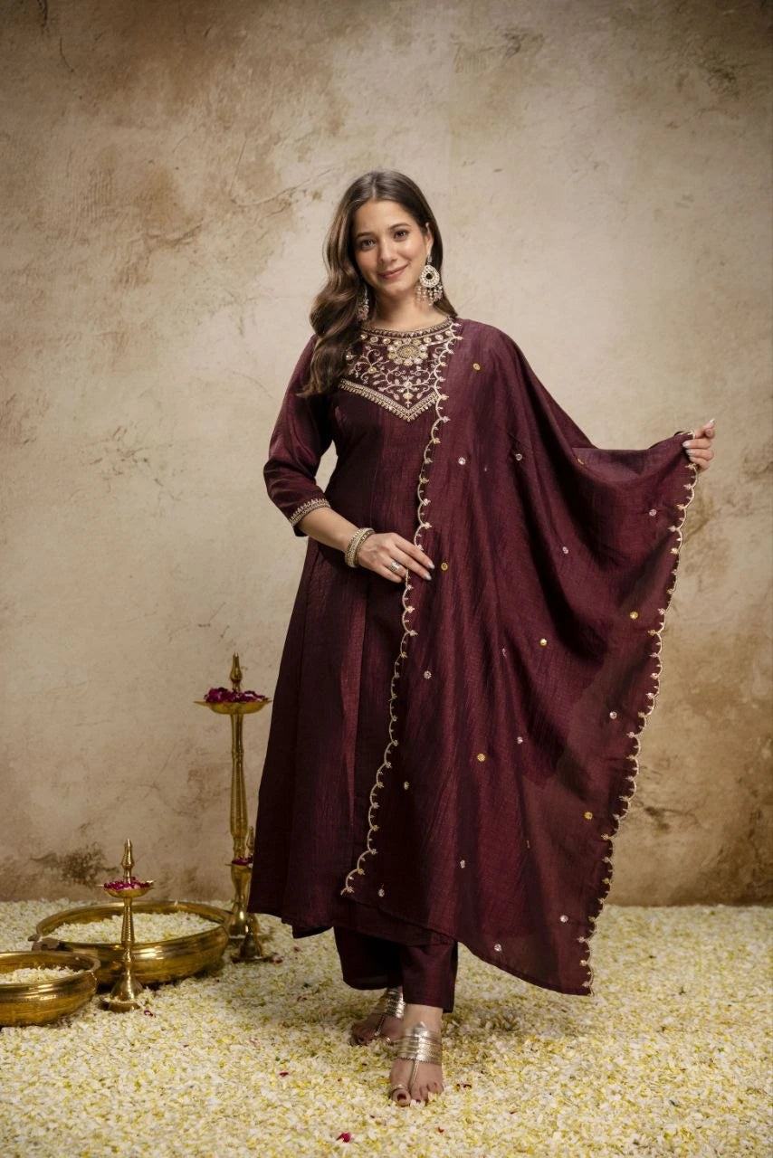 Woman in a maroon traditional outfit with jewelry against a beige background