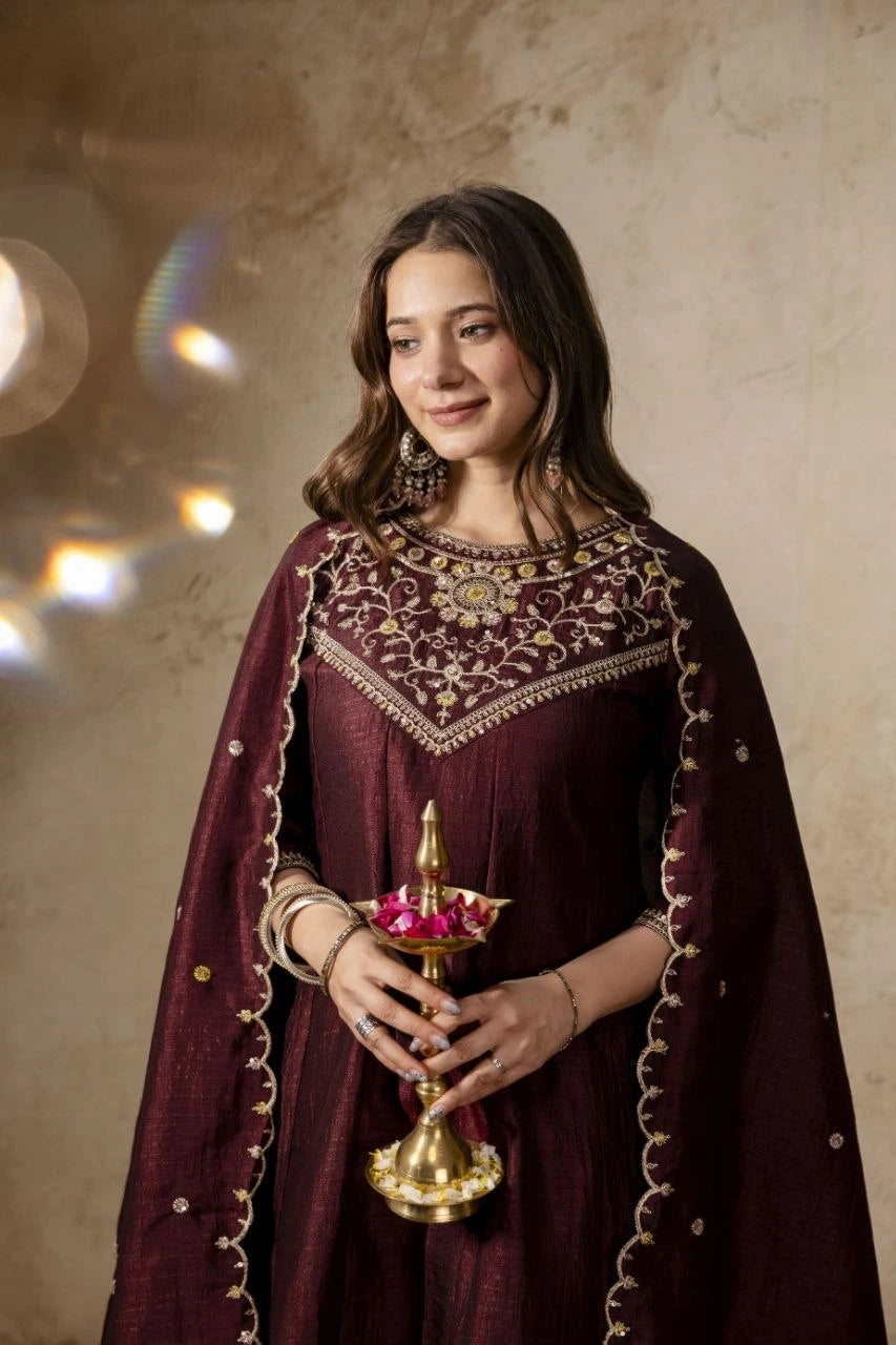 Woman in traditional attire holding a decorative lamp against a beige background