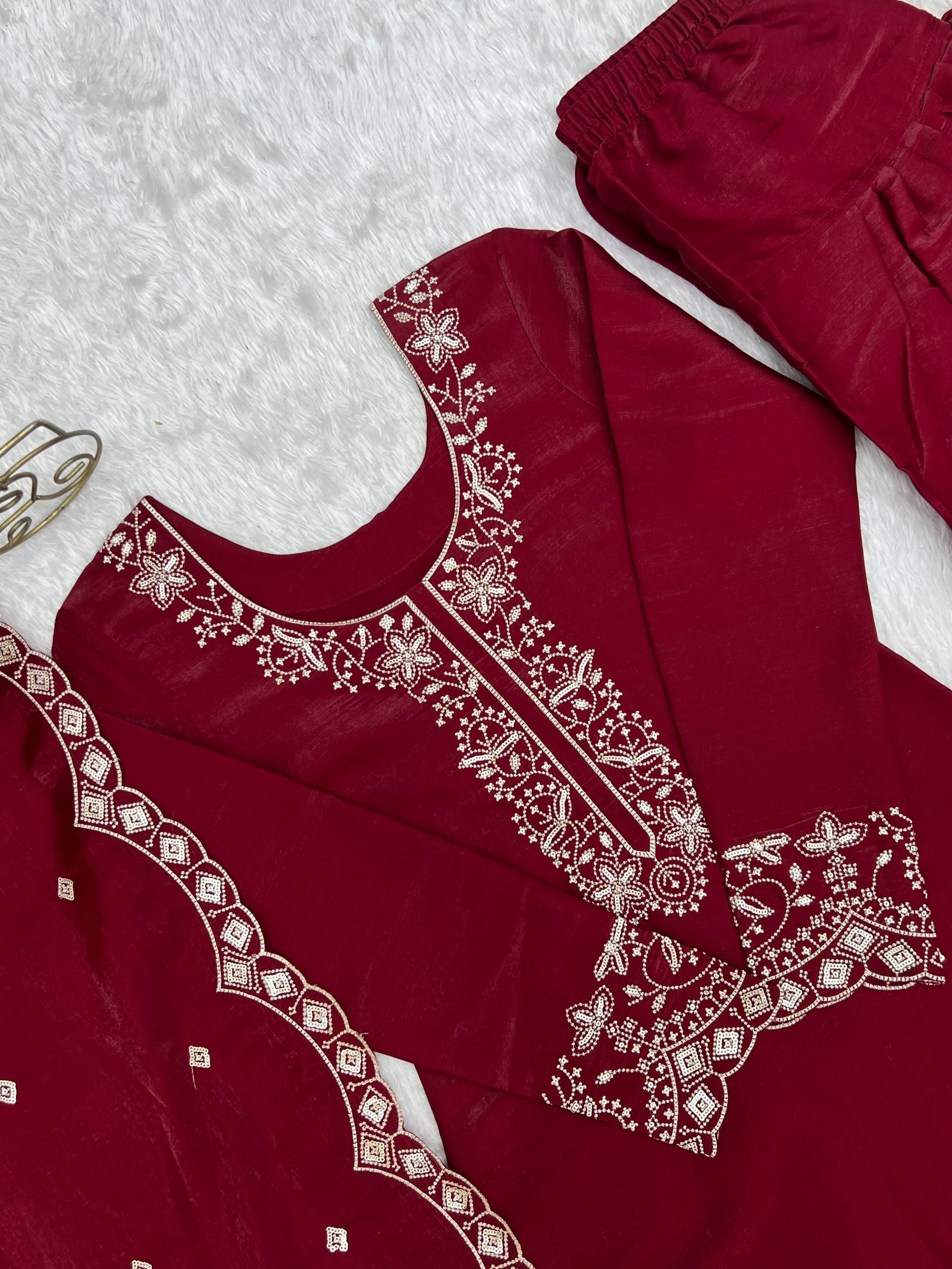 Maroon traditional outfit with white embroidery on a textured surface