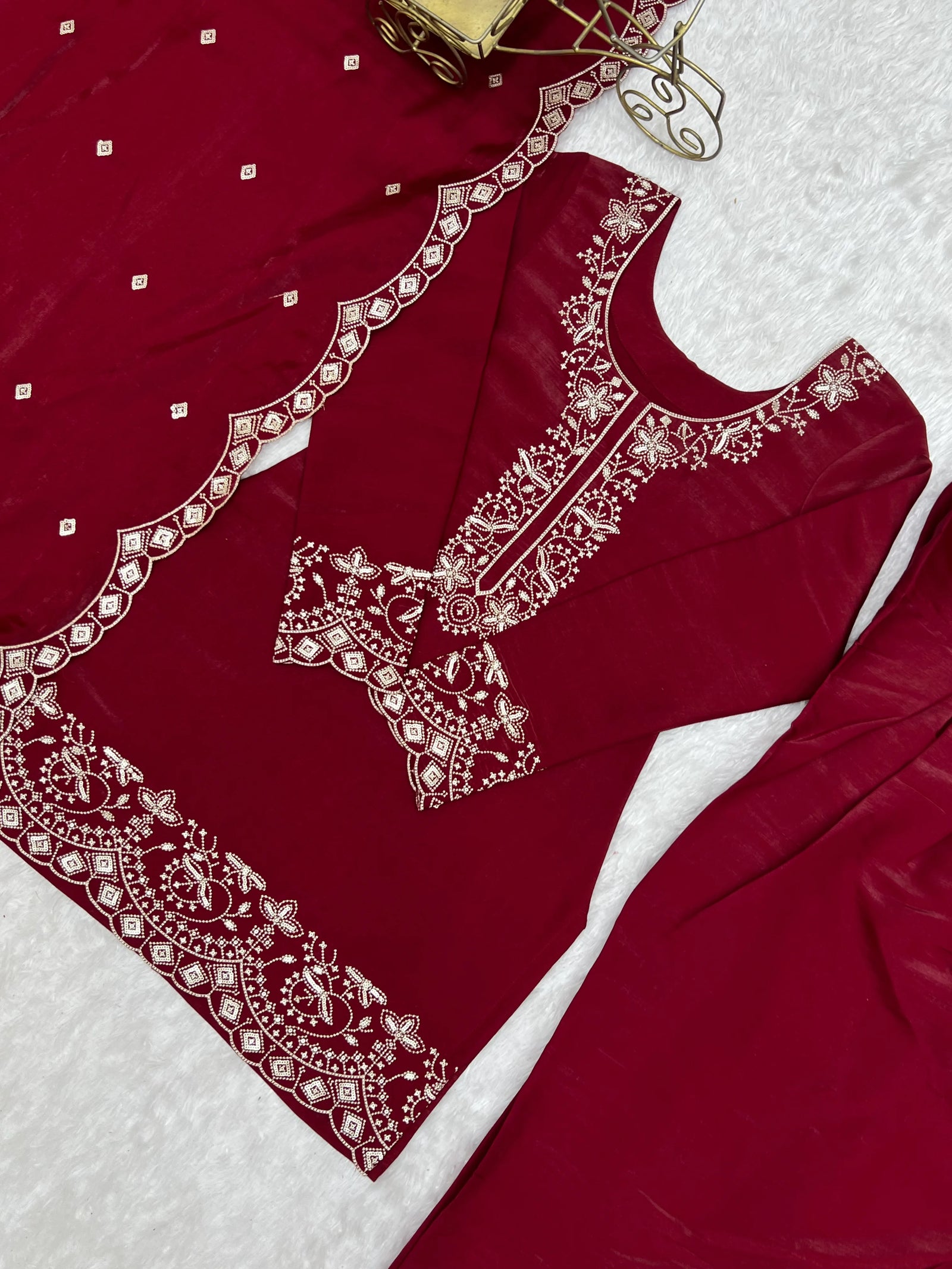 Red garment with intricate white embroidery on a textured white background