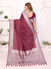 Woman wearing a maroon saree with white patterns in a bright room.