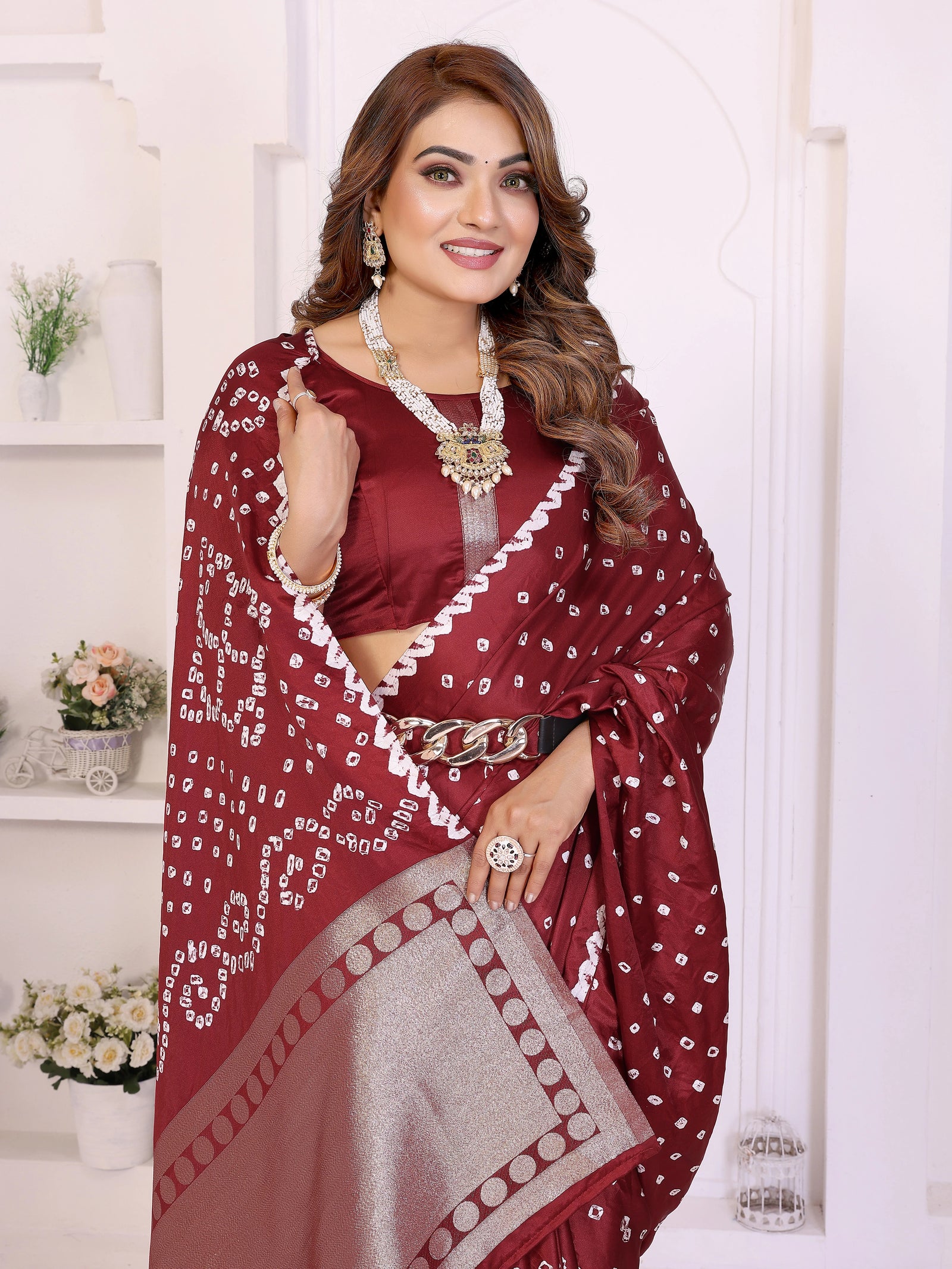 Woman wearing a maroon saree with white patterns in a well-lit room.