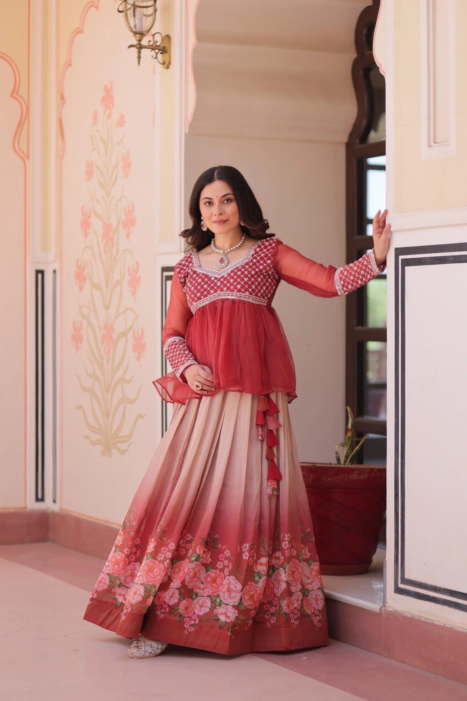 Woman in a red and white traditional outfit with floral design indoors.