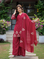 Woman in a red traditional outfit with floral patterns standing outdoors.