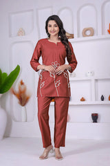 Woman wearing a red outfit with white floral patterns in a minimalistic room.