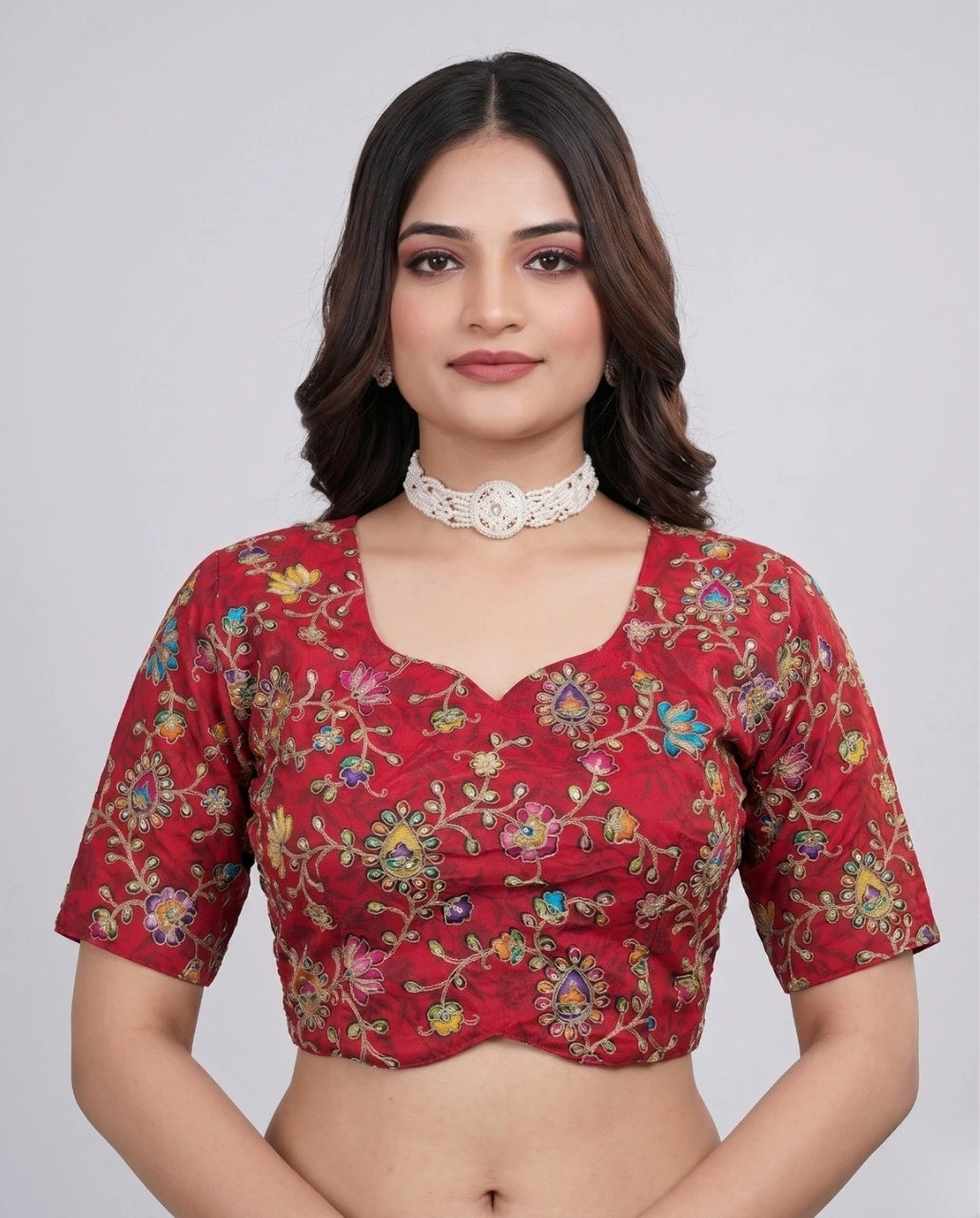 Woman wearing a red blouse with floral patterns on a plain background