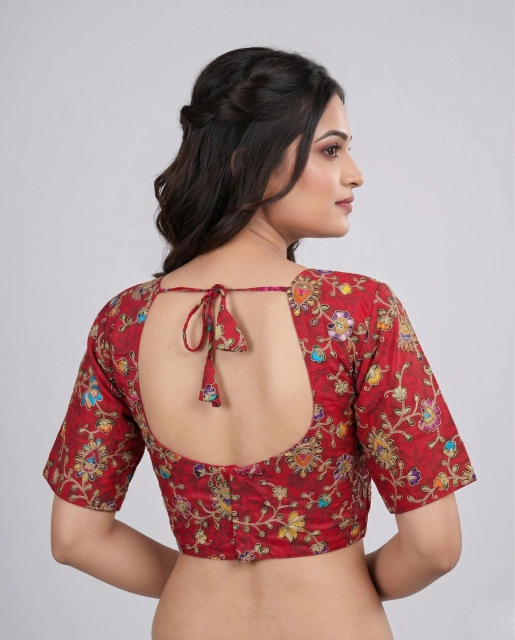 Woman wearing a red floral blouse with a backless design on a plain background