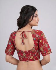 Woman wearing a red floral blouse with a backless design on a plain background