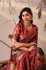 Woman in a red and black saree sitting on a chair with a neutral background