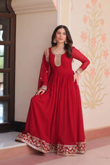 Woman wearing a red traditional outfit with gold embroidery in a decorated room.
