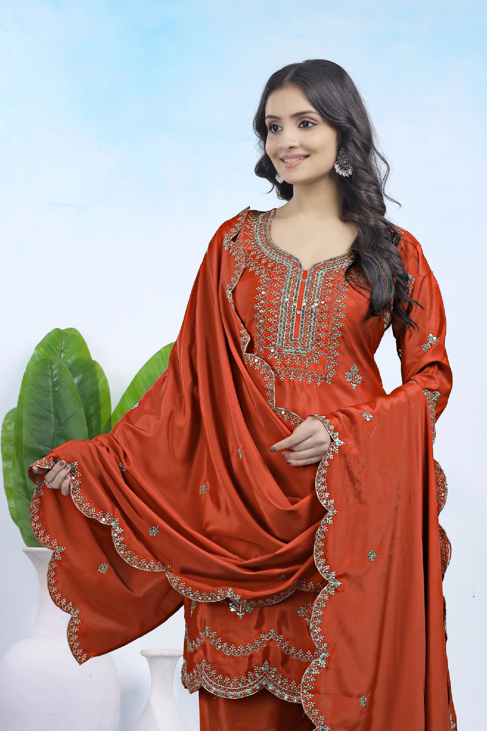 Woman wearing a red traditional outfit with intricate embroidery against a white background
