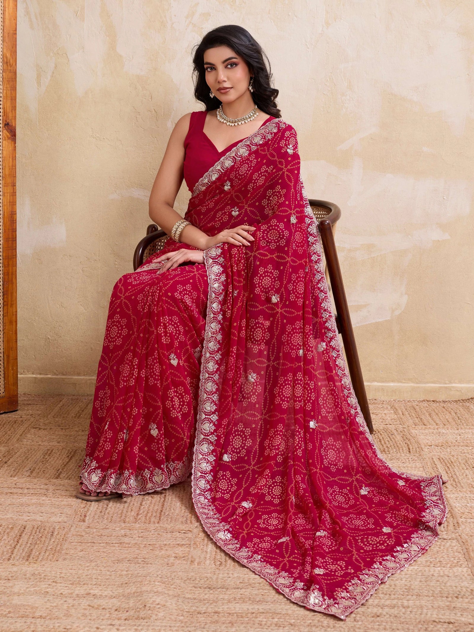 Woman wearing a red saree with white patterns on a beige background