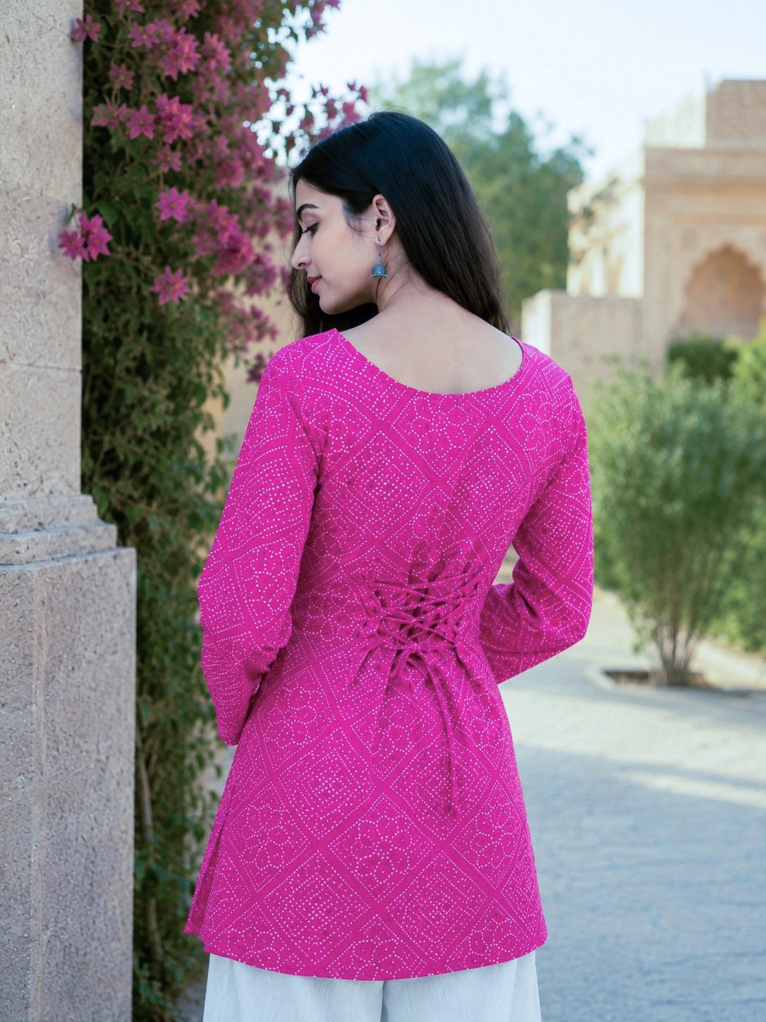 Woman wearing a pink embroidered dress with a blurred outdoor background