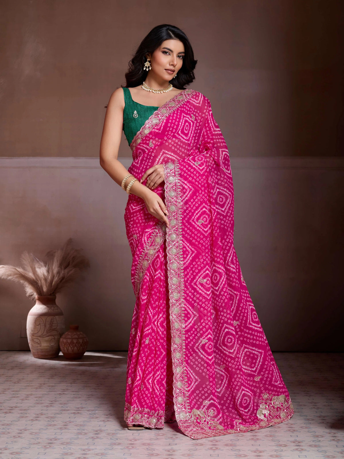 Woman wearing a pink saree with a patterned border against a neutral background