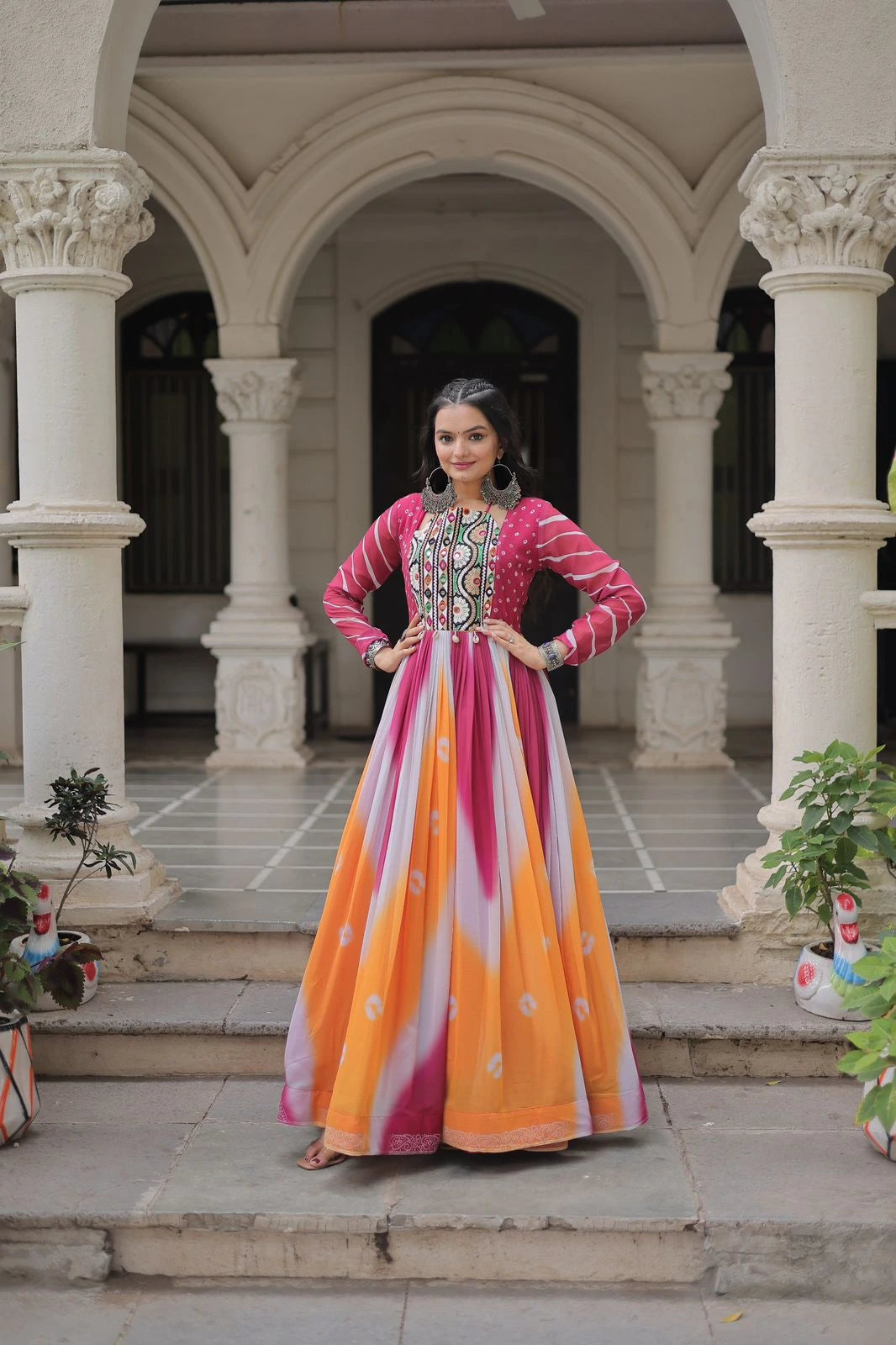 Woman in a colorful traditional outfit standing in an architectural setting with columns.