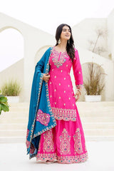 Woman in a pink traditional outfit with blue dupatta standing against a white background