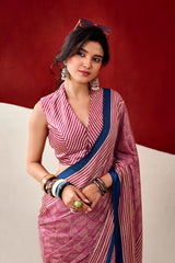 Woman wearing a pink and white striped saree with a blue border against a red background
