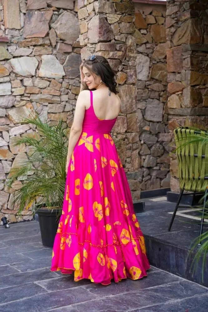 Woman in a pink and yellow dress standing in front of a stone wall.