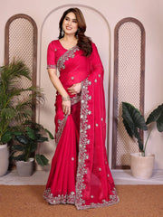 Woman wearing a bright pink saree with silver embroidery in an indoor setting.