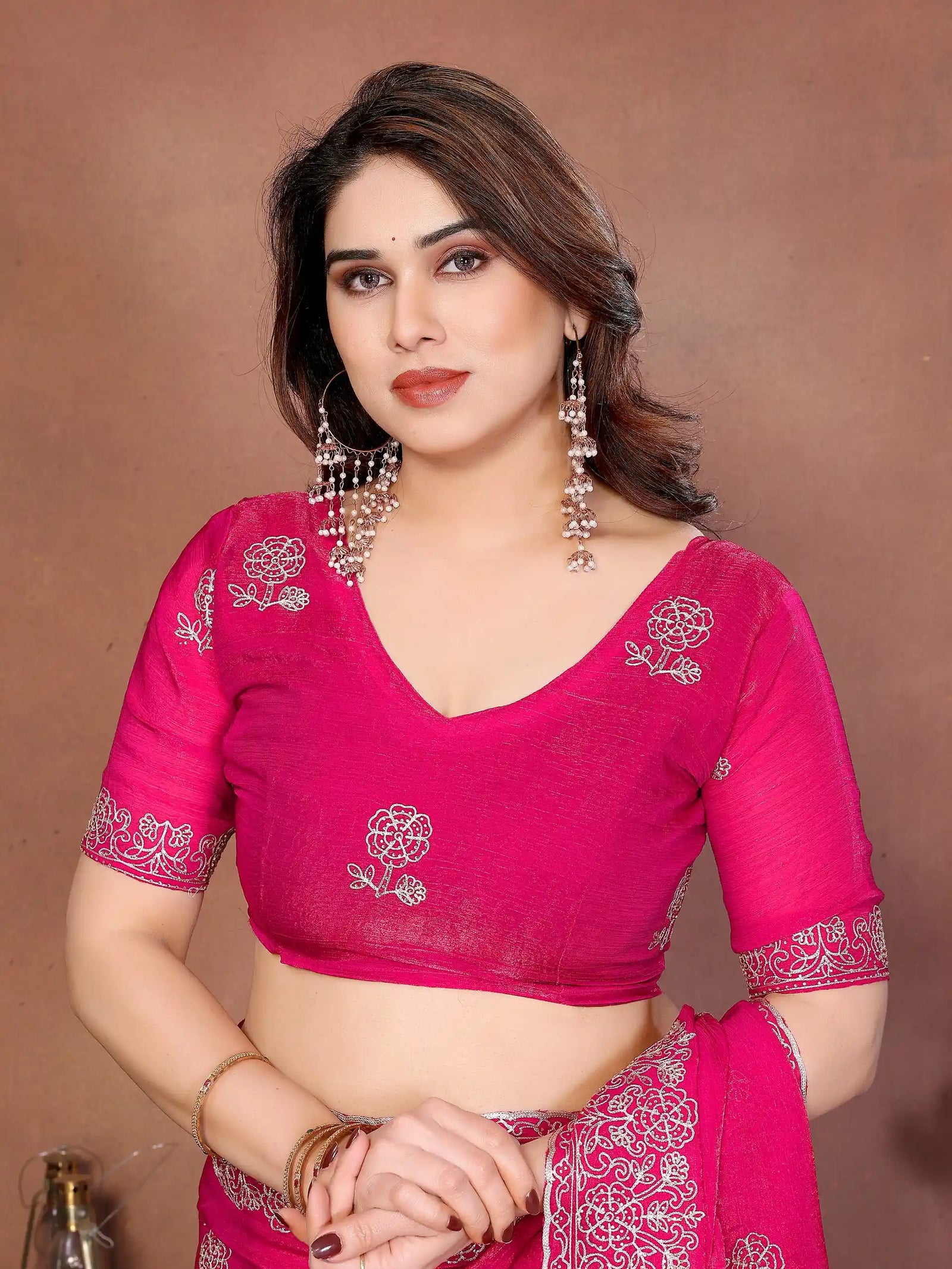 Woman wearing a pink saree with a brown background