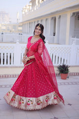 Woman in a red saree with a white building and potted plant in the background