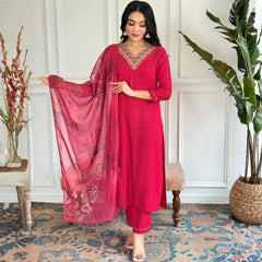 Woman in a red traditional outfit with a matching dupatta in a room with decorative elements.