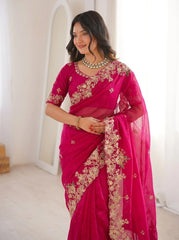 Woman wearing a pink saree with gold embroidery in a bright room.