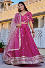 Woman in a pink traditional outfit standing in front of a yellow building.