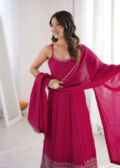 Woman in a pink traditional outfit with a matching dupatta, standing indoors.