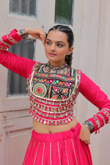 Woman in traditional outfit with colorful jewelry and pink top and skirt.