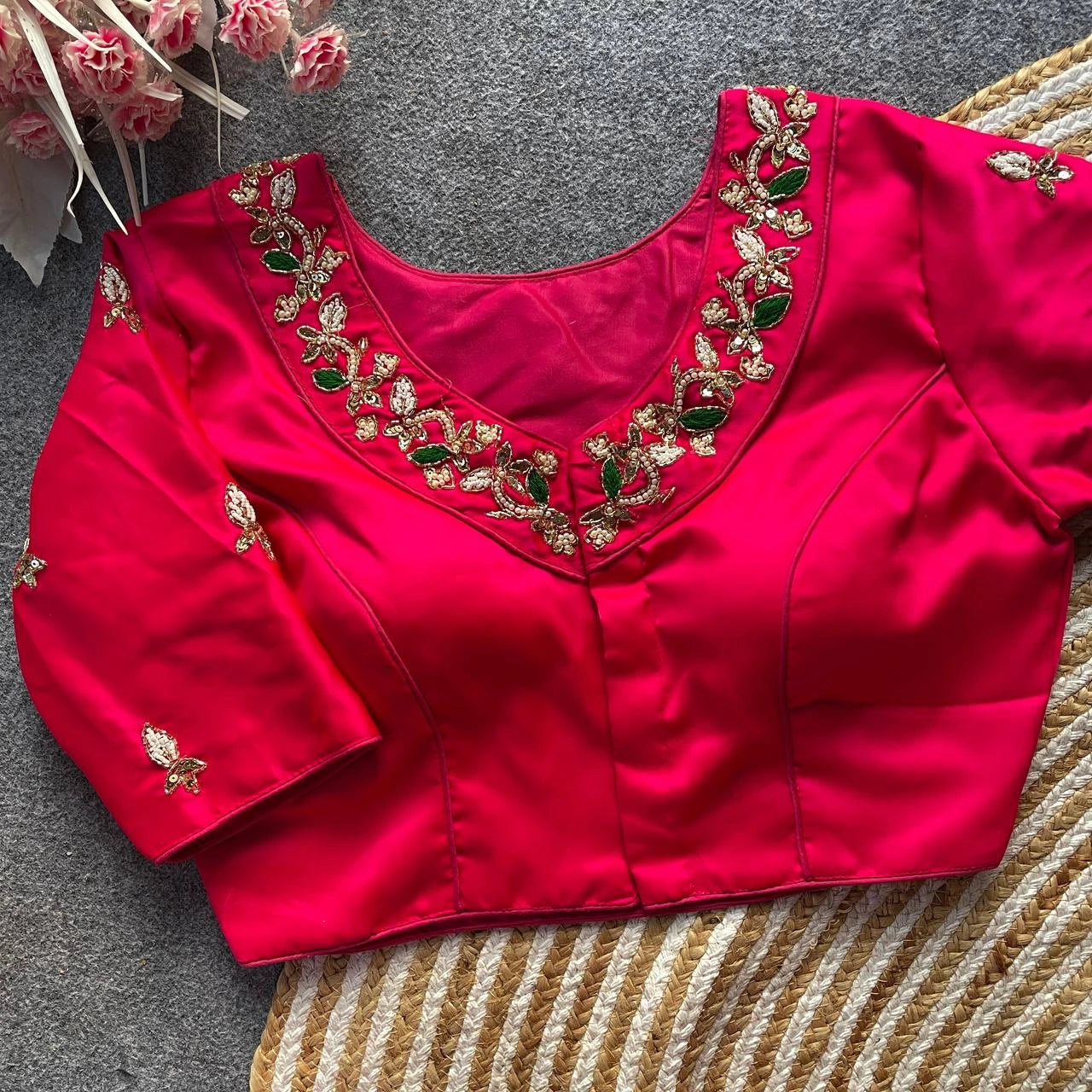 Red blouse with gold and green embroidery on a textured surface