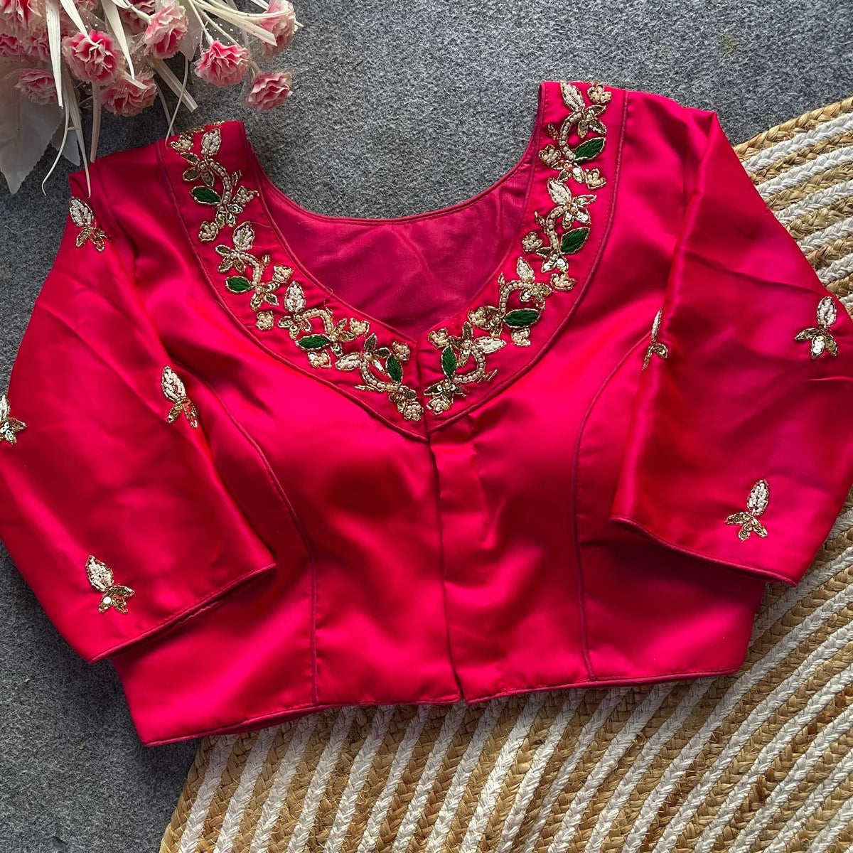 Red blouse with gold and green embroidery on a textured surface