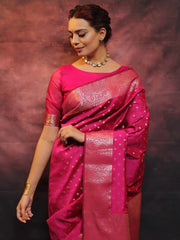 Woman wearing a pink saree with a metallic border against a dark background