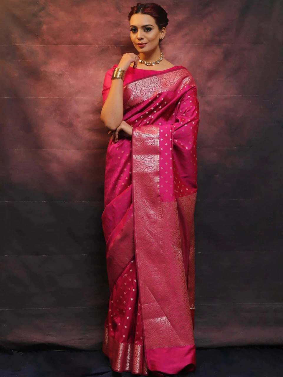 Woman wearing a pink saree with a dark background
