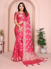 Woman wearing a pink saree with white patterns in a decorated room.