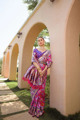 Woman in a colorful saree standing against a beige wall with arches.