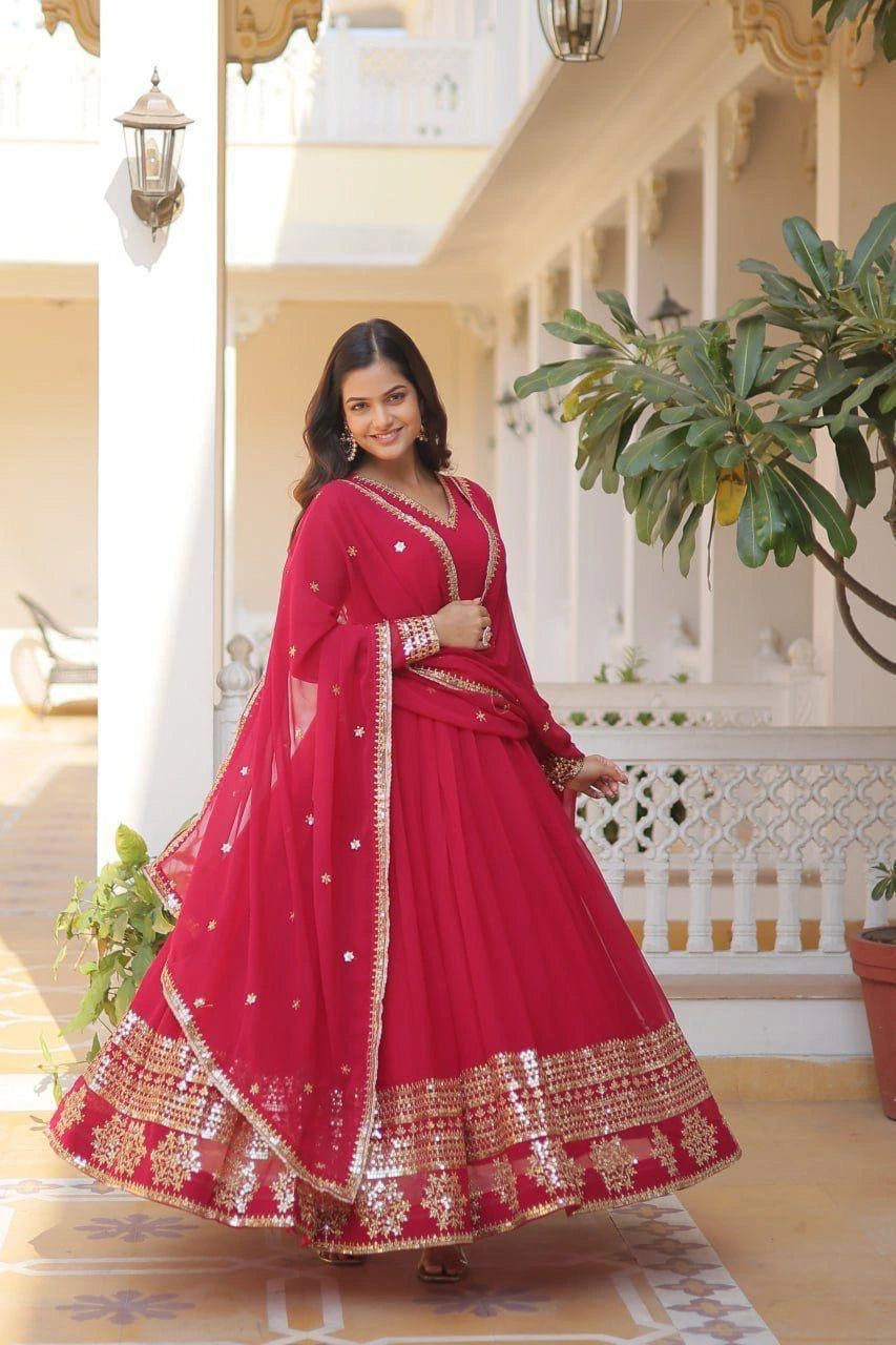 Woman in a red traditional outfit standing in an elegant indoor setting.