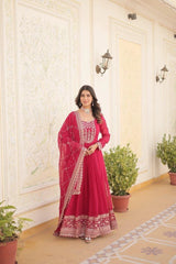 Woman in a red traditional outfit standing in a decorated room with plants.