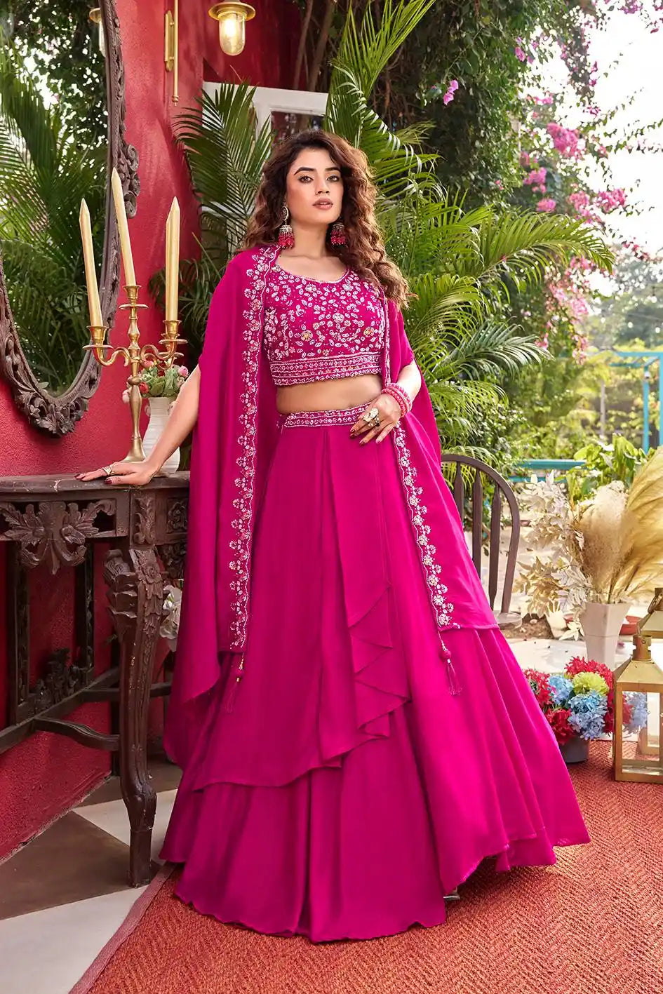 Woman in a vibrant pink traditional outfit with floral patterns in an outdoor setting.