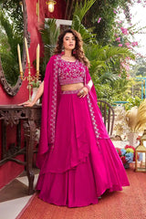 Woman in a vibrant pink traditional outfit with floral patterns in an outdoor setting.