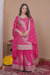 Woman wearing a pink embroidered traditional outfit with a beige background